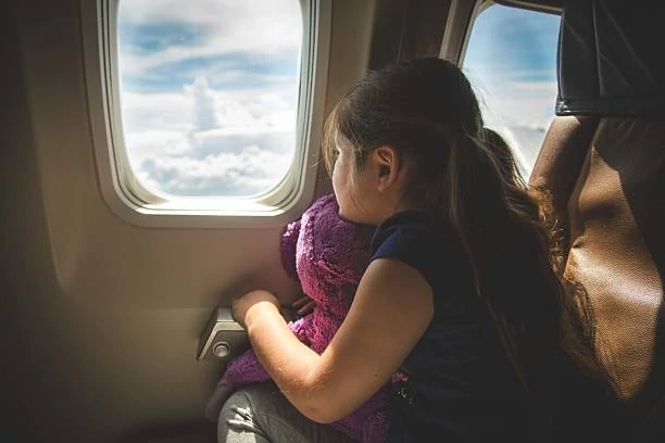 girl looking out window into the sky on an Airplane