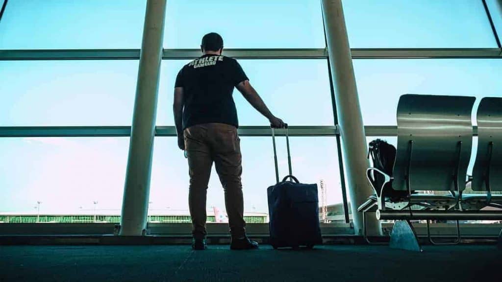 man looking out a window at an airport